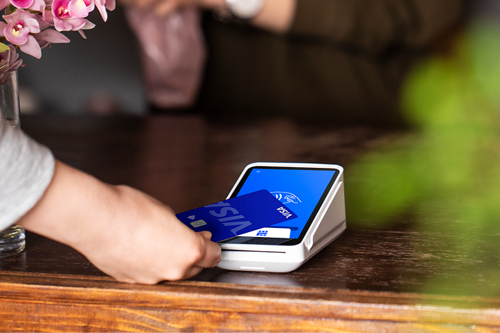 El icónico datáfono Square Reader de color blanco sobre un mostrador de madera, listo para aceptar pagos contactless.